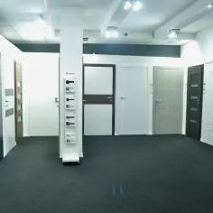 Salon z drzwiami i oknami, prezentujący różne modele drzwi wewnętrznych i zewnętrznych.