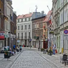 Ulica w Bydgoszczy z kamienicami i brukowaną nawierzchnią.